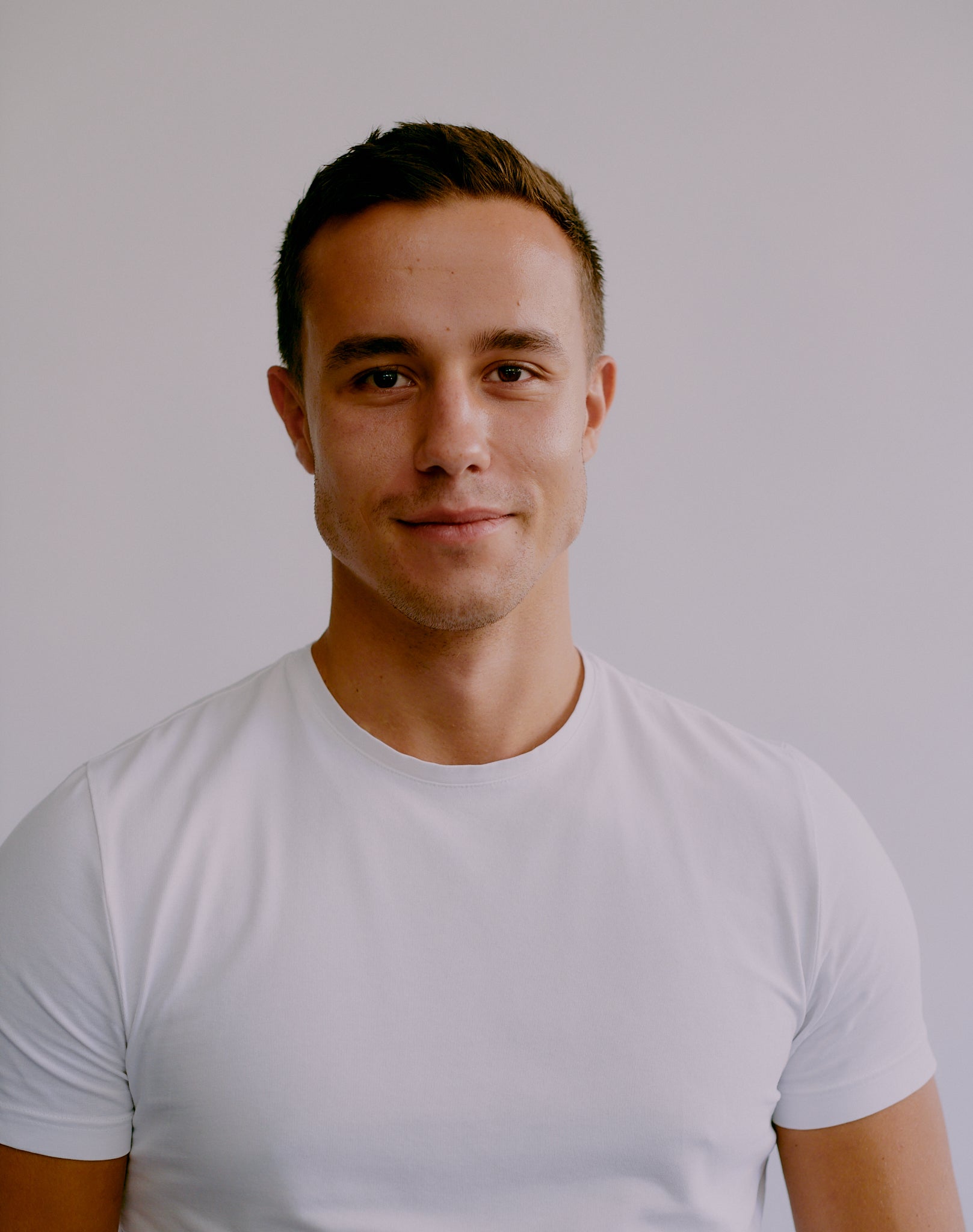 a portrait photo of Nate Michaels the co-founder of fjör standing in a white shirt with a white background