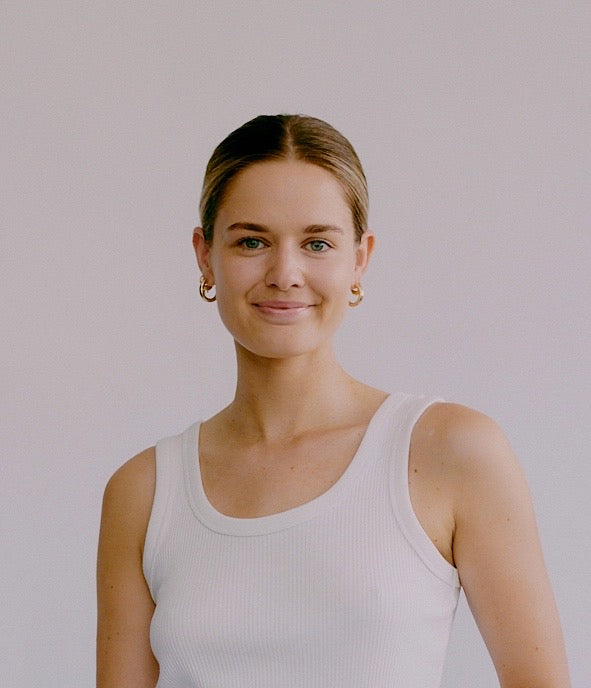a portrait photo of Rosie McKeown the Marketing Coordinator of fjör standing in a white shirt with a white background