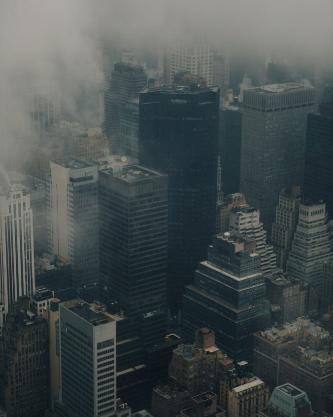 a birdseye view of a city landscape of buildings with a layer of clouds and smog