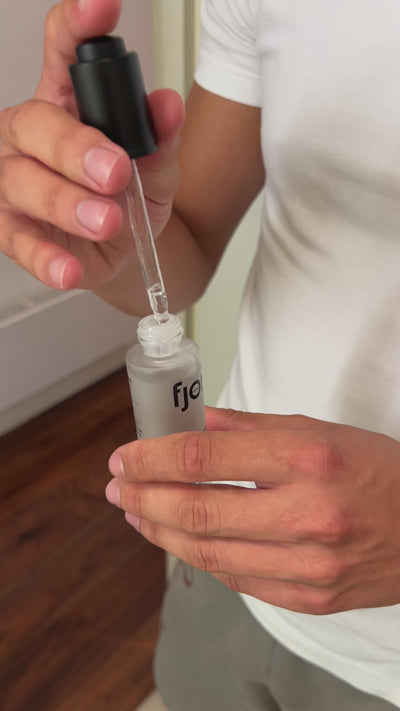 a male hand applying the hydrolytic enzyme on a hand with the pipette and push dropper in view